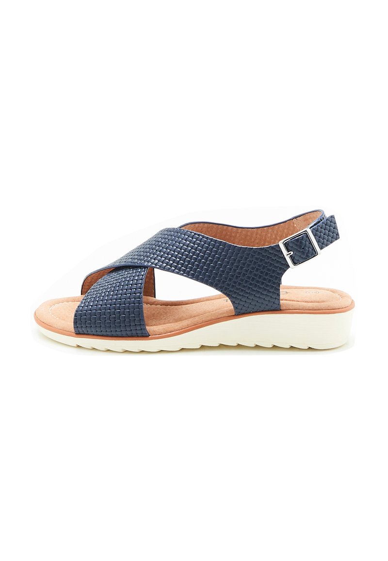 Sandal in tessuto blu navy con cinturini incrociati, dotata di una cinghia alla caviglia con fibbia, soletta imbottita beige e suola bianca testurizzata.