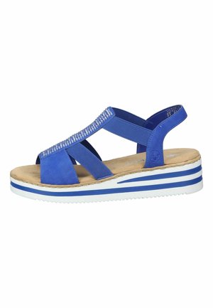 Sandale bleue avec des brides croisées, un rembourrage texturé et une épaisse semelle avec des rayures bleues et blanches. Accentuée de strass sur les brides.