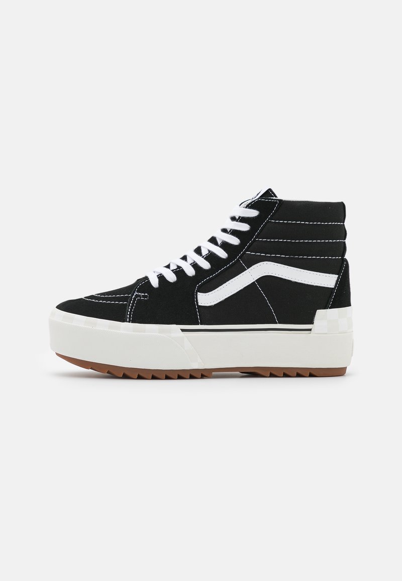 Czarne sneakersy typu high-top z zamszu, białymi sznurowadłami, białym paskiem po boku oraz teksturowaną gumową podeszwą z wzorem w zygzak.