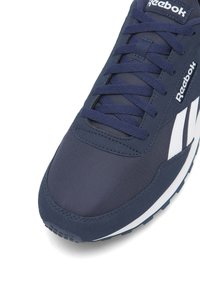 Sneakersy Reebok w ciemnym granacie, wykonane z siateczki i materiałów syntetycznych, z białymi akcentami, okrągłym noskiem i teksturowaną gumową podeszwą.