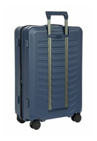 Hartschalentrolley in Marineblau mit vertikalem Rillenmuster, vier Rollen und einem teleskopierbaren Griff mit Aluminiumakzenten.