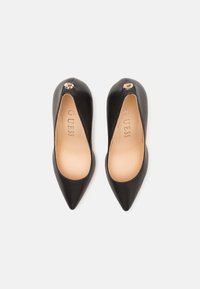 Black leather high-heeled shoes with a pointed toe and a low-cut design, featuring a gold accent logo on the heel and a smooth texture.