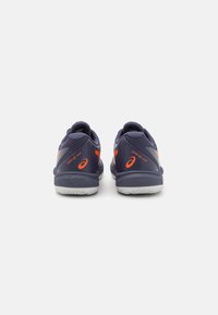 Baskets navy avec des accents orange, présentant une tige texturée, un col rembourré et une semelle en caoutchouc blanc pour l'adhérence.