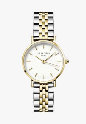 Reloj de acero inoxidable en oro y plata con una esfera blanca redonda, marcadores minimalistas y una pulsera metálica bicolor. Presenta una corona en el lateral.