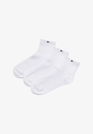 Trzy pary białych skarpetek za kostkę z prążkowanymi ściągaczami, każda z małą czarną literą "F" na białej metce u góry.