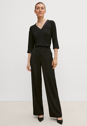 Black V-neck blouse with three-quarter sleeves, paired with high-waisted black wide-leg trousers, featuring a smooth texture and tailored fit.