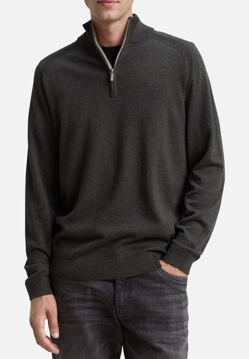 Pull-over en gris foncé avec un zip quart, des poignets et un ourlet côtelés, et un petit logo sur la poitrine gauche, fabriqué en matériau doux.