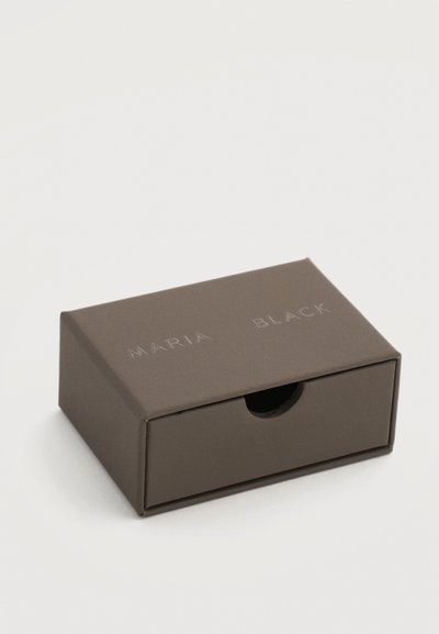 Μικρό, κλειστό, ορθογώνιο κουτί κοσμημάτων σκούρου καφέ χρώματος με συρτάρι που τραβιέται και την ένδειξη «MARIA BLACK» χαραγμένη στο πάνω μέρος.