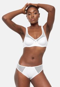 Conjunto de lingerie blanca que incluye un sujetador con paneles de malla y tirantes más gruesos, acompañado de una braga a juego con acentos de malla y bordes ondulados.