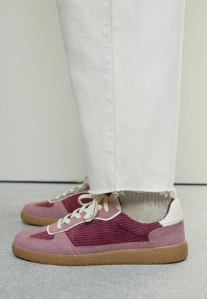 Sneaker in hellem Pink und Burgunder, mit Materialien aus Wildleder und Cordstoff, beige Schnürsenkeln und einer hellbraunen Gummisohle. Weiße Fersenelemente.