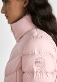Απαλή ροζ μπουφάν πούφερ με ψηλό γιακά, οριζόντια ραφιναρίσματα και κυκλικό λογότυπο Colmar στη πάνω πλευρά του μανικιού. Ομαλή υφή.