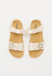 Lichtgekleurde leren sandalen met een gevoerd voetbed, gegolfde randen en een decoratieve glitterschelp op de band.