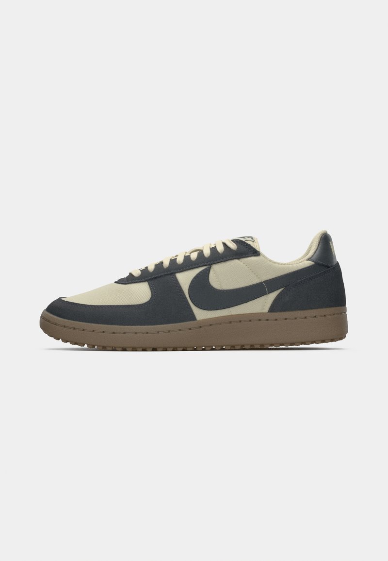 Donkerblauwe en crèmekleurige sneaker met een gestructureerde bovenkant, voorzien van een contrasterend swoosh-logo, platte veters en een bruine rubberen buitenzool.
