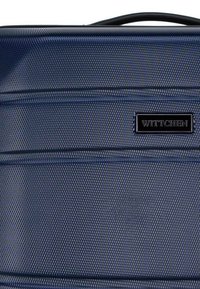Navy blue travel bag with a textured exterior, featuring horizontal lines and a black logo plaque. Durable material and sturdy handle.