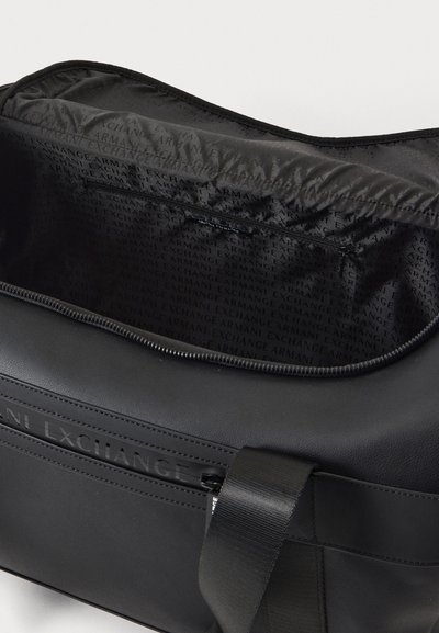 Отворена черна спортна чанта Armani Exchange, показваща подплатата с логото на марката, вътрешен джоб с цип, външен цип и широка презрамка за рамо.