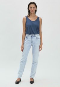Donkerblauwe tanktop, lichtblauwe high-waisted jeans en zwarte puntige ballerina's. Rechtonde ontwerp, minimalistische stijl en geen opvallende patronen.