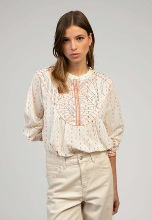 Blouse à manches longues en tissu léger crème avec des pois multicolores, panneau avant brodé et encolure ronde.