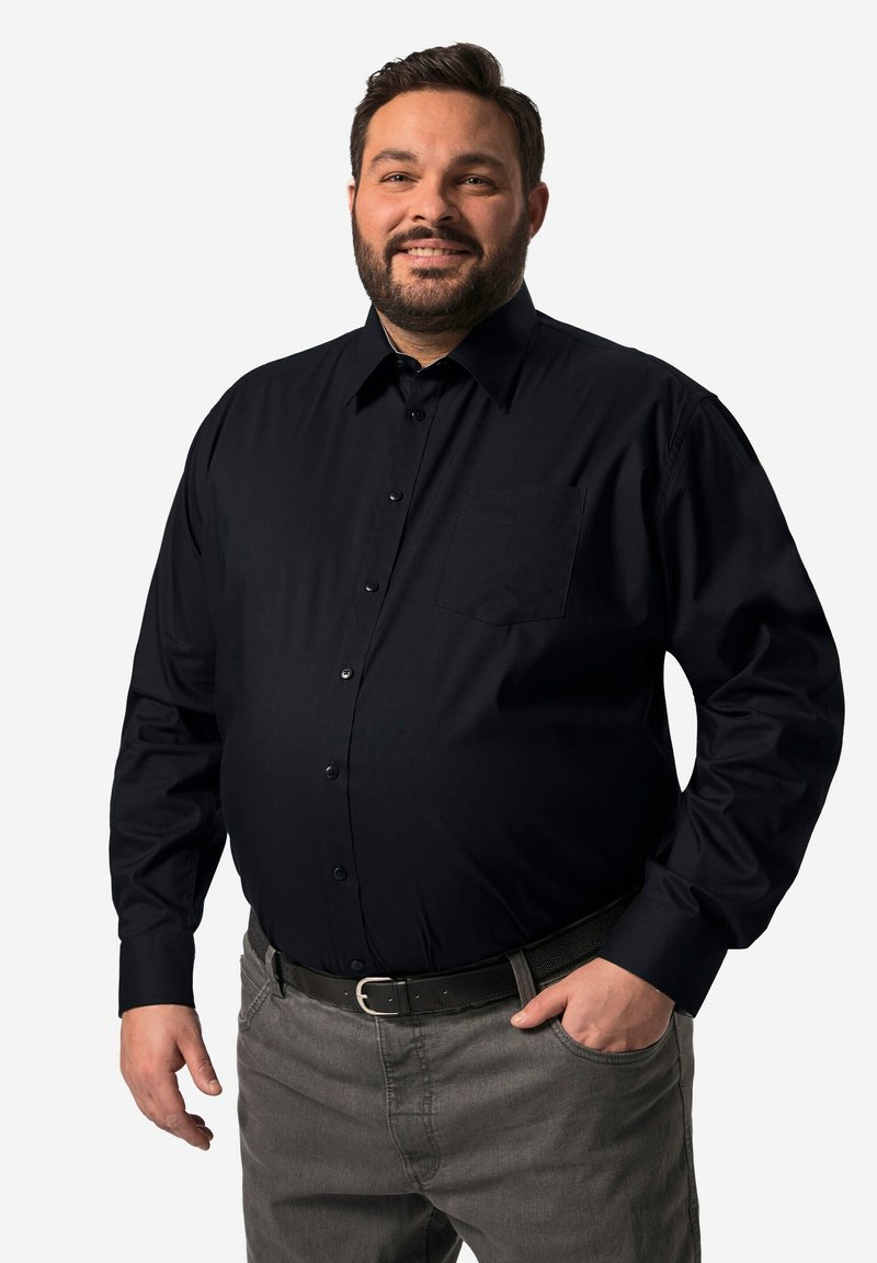 Zwarte langemouwen overhemd met knopen en een borstzak, gladde textuur en een gestructureerde kraag, gedragen over grijze broek met een zwarte riem.