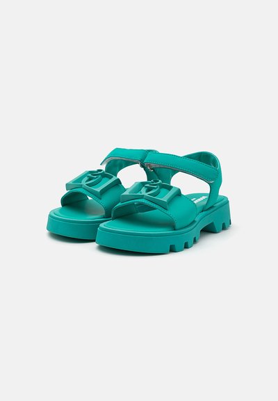 Turkosa sandaler med tjock sula, justerbara remmar och logotypdetaljer fram. Har öppen tå och utskärningsdesign för bättre andningsförmåga.
