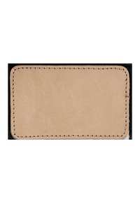 Suorakaiteen muotoinen beige nahkapala pyöristetyillä kulmilla ja näkyvillä saumoilla reunoilla, tummalla taustalla.