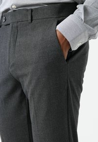 Grijze op maat gemaakte broek met een gladde textuur, een platte voorkant, zijzakken en een regular fit, gecombineerd met een lichtblauw overhemd met manchetknopen.