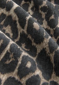 Tissu à imprimé léopard avec un motif texturé noir et beige. Présente des taches contrastées et une texture lisse légèrement côtelée.