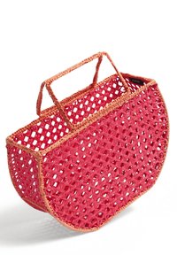 Tkany koszyk w jasnoróżowym kolorze z brązowymi akcentami, o półokrągłym kształcie, z otwartym splotem i dwoma krótkimi uchwytami do noszenia.