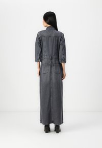 Denim lang kjole i mørkegrått med oppbrettede ermer, innsvingt midje, to baklommer og knappelukking langs baksiden.