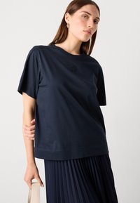Navy blue short-sleeve t-shirt made of smooth fabric, featuring a subtle embroidered logo on the chest and a relaxed fit.