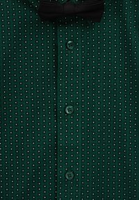 Tamnozelena košulja s kvadratnim uzorkom i malim bijelim točkicama, s dugmetima i crnim leptir-mašnom pričvršćenom na ovratniku.