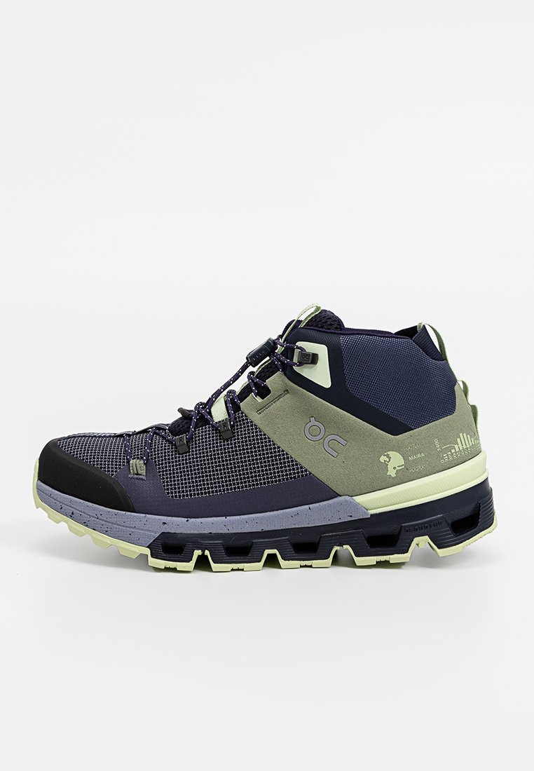 Wysokie buty trekkingowe w granatowej siateczce z szarymi i zielonym akcentami, z teksturowanym wykończeniem, gumowym noskiem oraz trwałą podeszwą zapewniającą przyczepność.