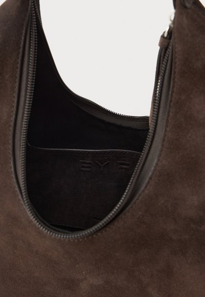 Borsa in suede marrone con forma arrotondata, chiusura con zip e branding interno. Presenta una consistenza morbida e una fodera liscia.