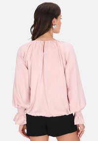 Blushfarbene Bluse mit langen, puffartigen Ärmeln, gerafften Manschetten und einem Schlüssellochdetail im Rücken. Glattes, leichtes Material mit weichem Fall.
