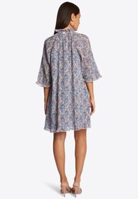 Floral dress in sheer fabric with a ruffled neckline, three-quarter bell sleeves, and a flared hem. Colors include pink, blue, and green patterns.