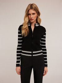 Zwarte ritscardigan met gestreepte mouwen, voorzien van witte en grijze accenten. Zachte gebreide stof, aansluitend design en een geribde tailleband.