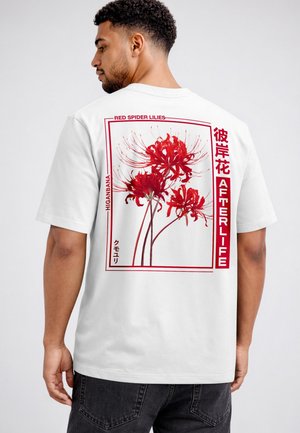 Man wearing a white t-shirt with a red spider lily flower graphic and text including "Red Spider Lilies," "Afterlife," and Japanese characters.