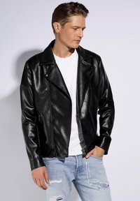 Schwarze Leder-Motorradjacke mit glänzendem Finish, ausgestattet mit einem Reverskragen, einem Reißverschluss vorne und zwei Seitentaschen, kombiniert mit ausgewaschenen blauen Jeans.