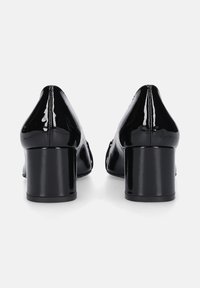 Tacchi in vernice nera con punta arrotondata e tacco spesso. Presentano cuciture sul retro e una superficie liscia e lucida.