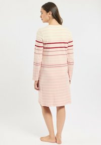 Robe à manches longues rayée en tissu doux, avec des rayures rose clair et bordeaux. Longueur genou avec une coupe décontractée et un col rond.