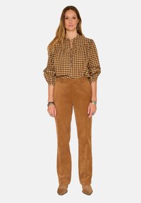 Chemisier à carreaux marron avec une patte de boutonnage, associé à un pantalon en velours côtelé marron et des chaussures pointues beige clair. Texture lisse tout au long.