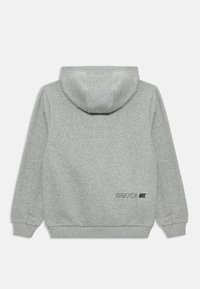 Moleton cinza da Nike com capuz, punhos e barra canelados, mostrando a parte de trás com pequeno texto preto e o logo da Nike perto do canto inferior direito.