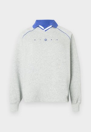 Vaaleanharmaa pitkähihaine huppari sinisellä kauluksella, siniset kantit harteilla ja "NIKE"-teksti ympyrälampun logolla rintapielessä.