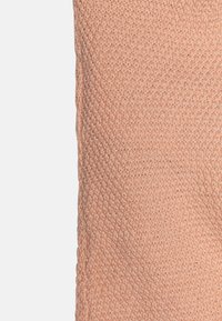 Nėriniai audinys švelnios persikų spalvos su tekstūruotu, kvėpuojančiu audiniu; turi vienodą raštą ir lankstų kritimą.