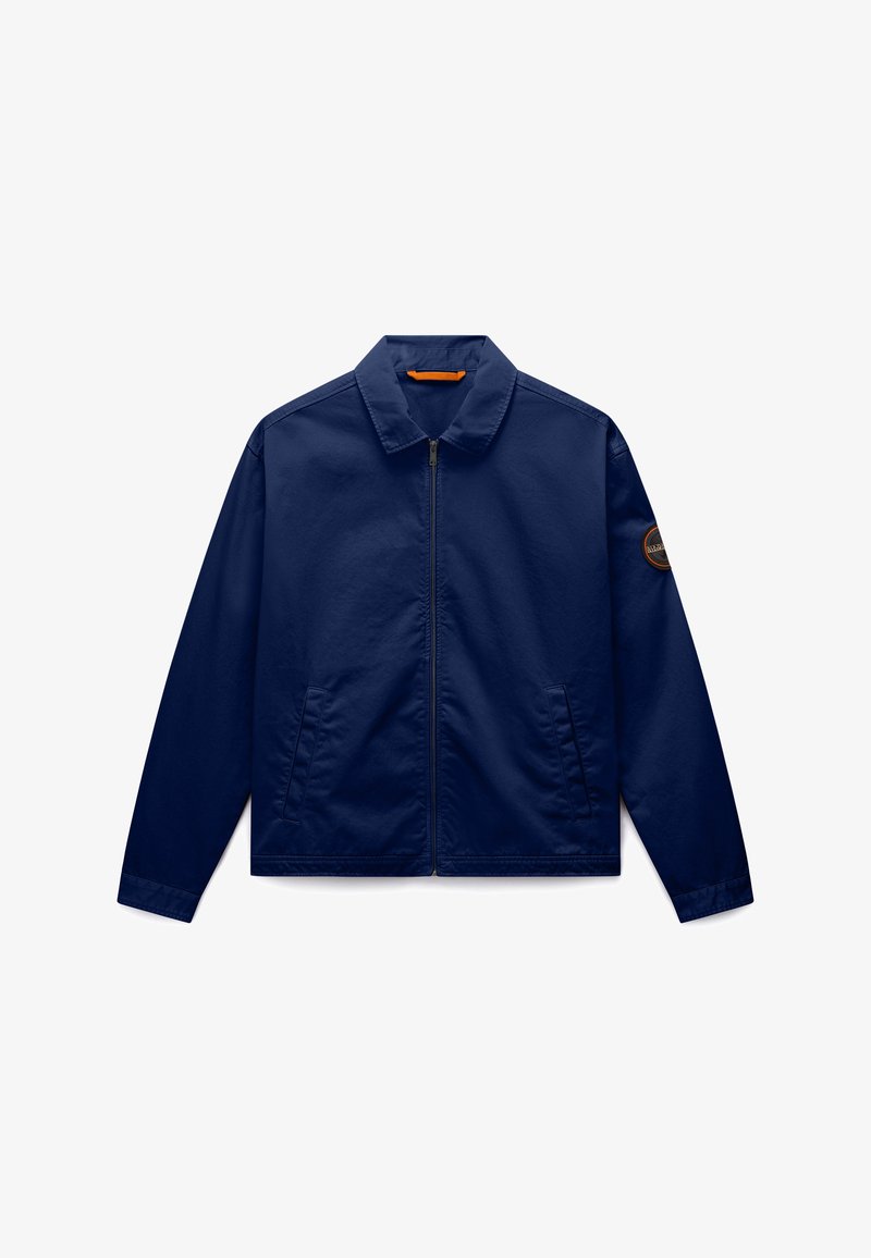 Veste zippée bleu marine avec col, poches latérales et un écusson rond sur la manche gauche, présentée sur un fond blanc.