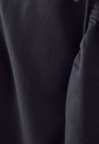 Black fabric, smooth texture, with a slight sheen. Features gathered detail on the edge, enhancing the structure and design.