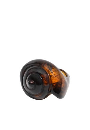 Anillo de resina ámbar oscuro con forma de espiral de concha de caracol, con superficie lisa y pulida sobre un fondo blanco.
