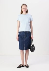Hele sinine puuvillane T-särk, mis on kombineeritud põlvepikkuse tumeda denim-seelikuga. Must käekott lühikese sangaga ja terava ninaga mustad baleriinad.