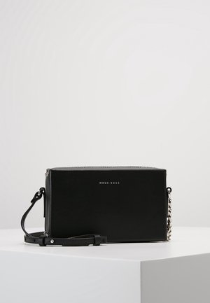 Sort rektangulær Hugo Boss crossbody taske med sølvkædedetalje og justerbar læderrem på en hvid overflade.