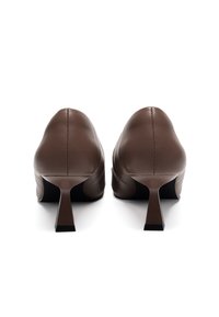 Scarpe con tacco alto in pelle marrone con punta arrotondata, cuciture minime e un design del tacco geometrico distintivo, con una finitura opaca.