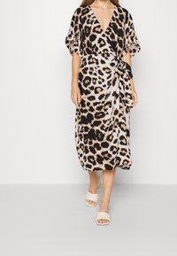 Vestido envolvente de estampado de leopardo en beige y negro, con mangas cortas, escote en V profundo y un lazo en la cintura. Tejido suave y ligero.